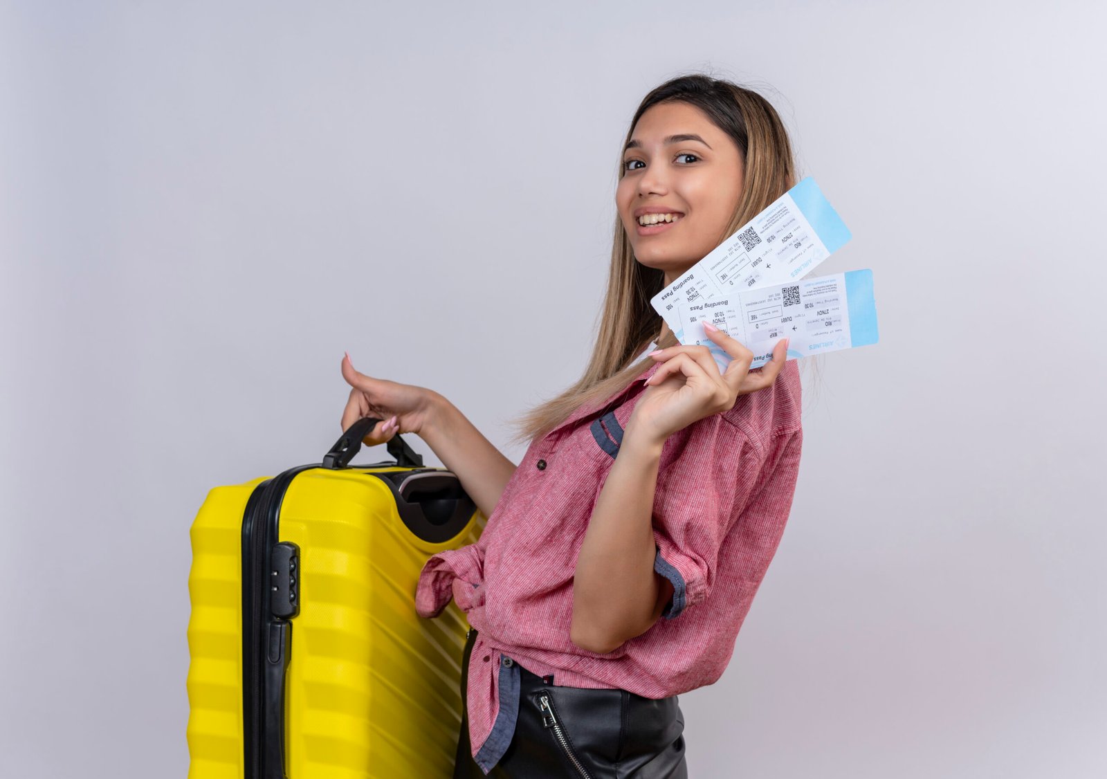 Pleased Young Woman Wearing Red Shirt Holding Yellow Suitcase With Plane Tickets While Looking White Wall Scaled